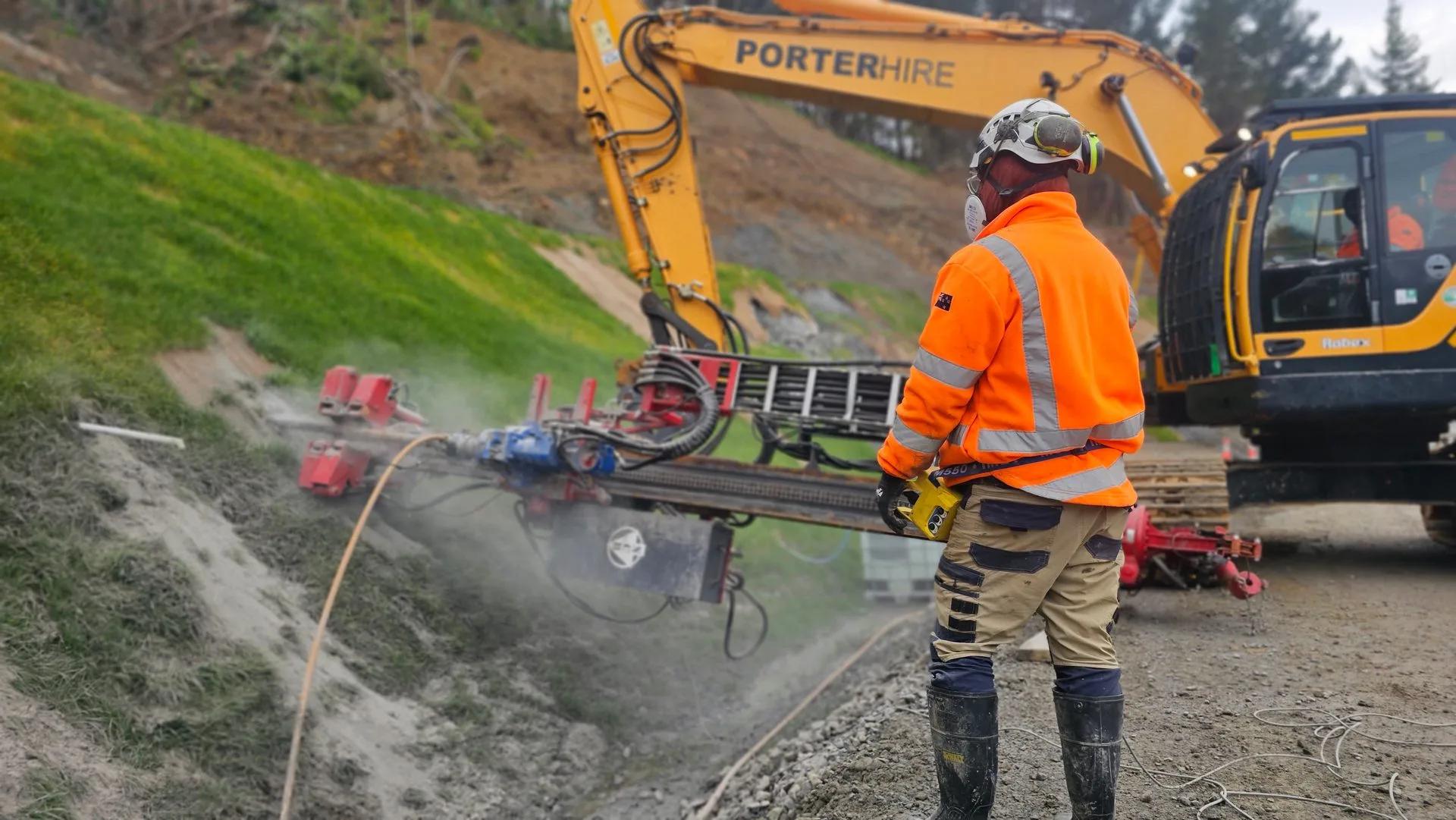 Cracked and subsided NZ rural road with orange cones marking the failed pavement section